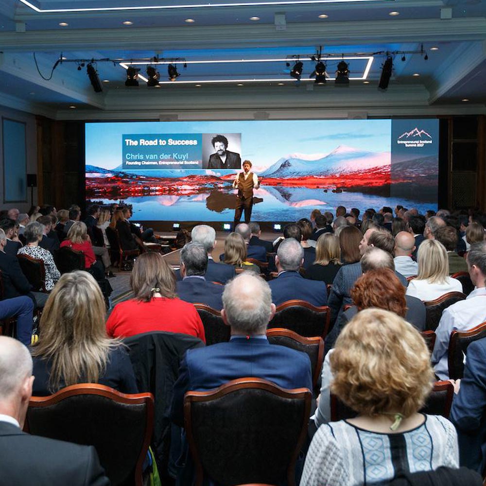 A photo of Chris van der Kuyt onstage addressing an audience at the Entrepreneurial Scotland Summit 2018 at Gleneagles Resort