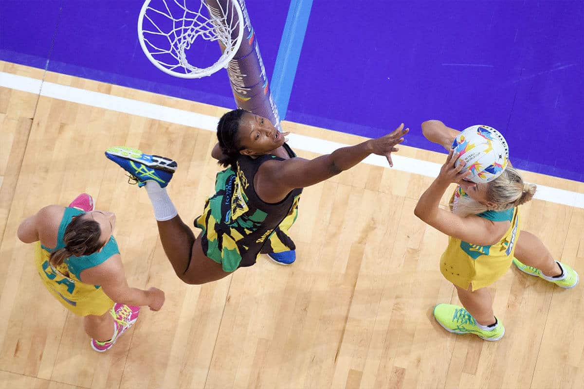 An action photo taken from high above the net, showing three women playing netball